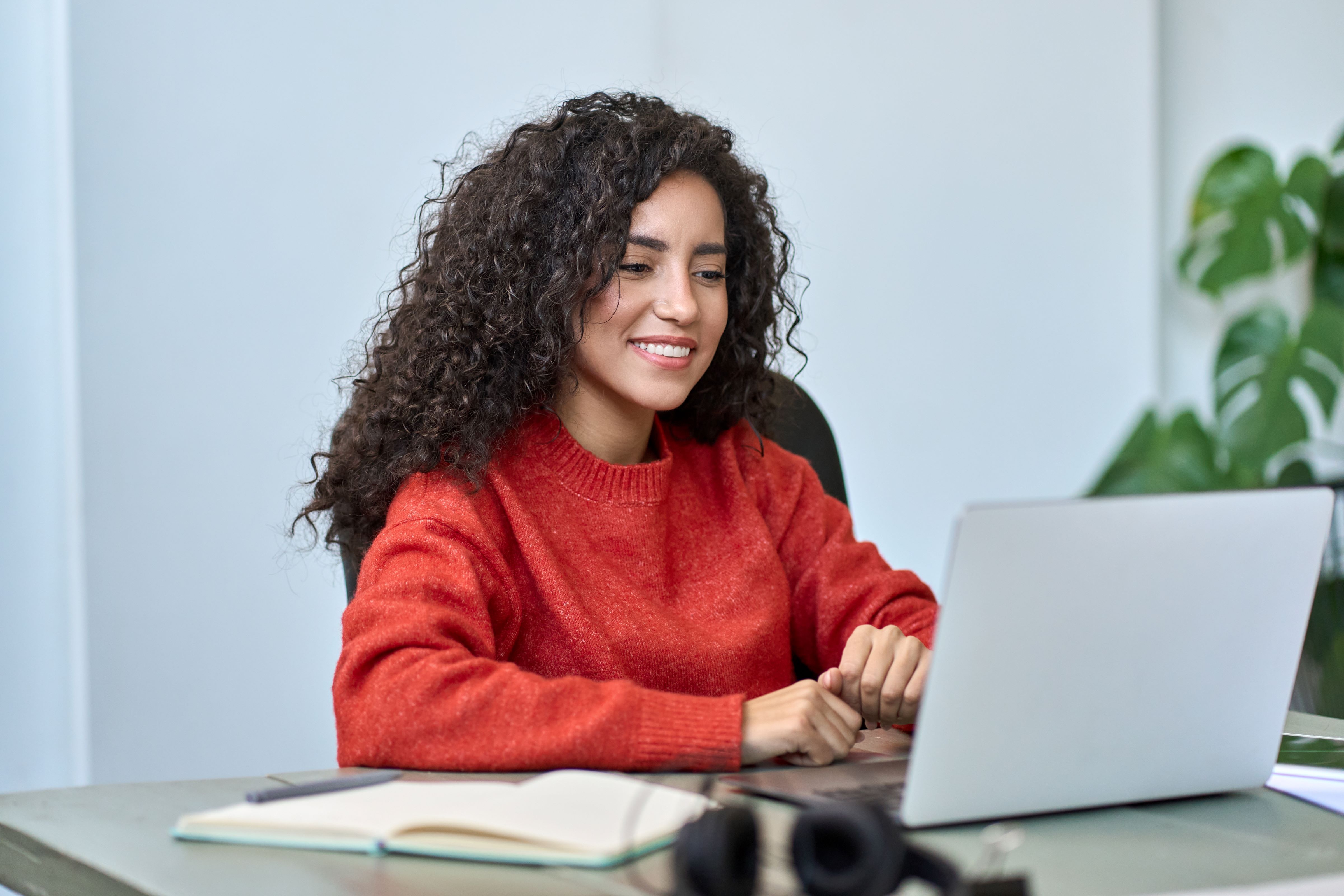Smiling woman holds a laptop.